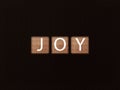 inscription JOY on wooden blocks on black background. Letter on wooden cube