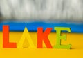 Inscription lake from multicolored bright wooden letters lie on a bright yellow background copy space. holiday vacation concept Royalty Free Stock Photo