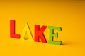 Inscription lake from multicolored bright wooden letters lie on a bright yellow background copy space. holiday vacation concept Royalty Free Stock Photo
