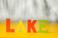 Inscription lake from multicolored bright wooden letters lie on a bright yellow background copy space. holiday vacation concept Royalty Free Stock Photo