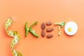 Inscription keto composed of vegetables and measuring tape on orange background