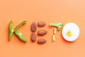 Inscription keto laid out of pepper, broccoli, eggs and almonds, on a orange background