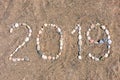 The inscription `2019` laid out by sea pebbles on the sand of the beach. Summer lettering on the coast