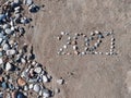 Inscription lined with stones in the sand 2021