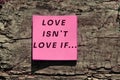 Inscription Love isn`t Love if... on pink paper on wrinkled bark surface with deep cracks