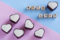 Inscription with love next to heart shaped chocolates made of dark and white chocolate. Pink and blue gendered background for