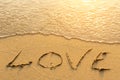 Inscription LOVE on sea beach sand, is soft the wave. Abstract. Royalty Free Stock Photo