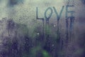 Inscription love on the wet glass rain