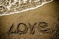 The inscription LOVE on a wet sand seacoast. Toned Royalty Free Stock Photo