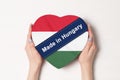 Inscription Made in Hungary the flag of Hungary. Female hands holding a heart shaped box. White background