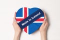 Inscription Made in Iceland the flag of Iceland. Female hands holding a heart shaped box. White background