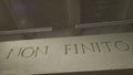 The inscription that means it is not the end on the grey wall. Isolated NON FINITO text, acronym of ancient Roman Empire