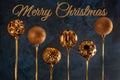 The inscription Merry Christmas on a dark blue, textural background. Six golden Christmas balls turned upside down