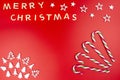 The Inscription Merry Christmas made of wooden letters, lying flat from above, isolated on a red background. Four candy canes visi Royalty Free Stock Photo