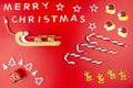 The Inscription Merry Christmas made of wooden letters, lying flat from above, isolated on a red background. Visible candy canes, Royalty Free Stock Photo