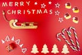 The Inscription Merry Christmas made of wooden letters, lying flat from above, isolated on a red background. Visible candy canes, Royalty Free Stock Photo