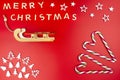 The Inscription Merry Christmas made of wooden letters, lying flat from above, isolated on a red background. Visible candy canes, Royalty Free Stock Photo