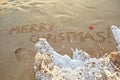 The inscription Merry Christmas on the sand on the beach.