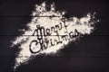 The inscription Merry Christmas , written with flour on a dark wooden background. Christmas greeting card. Royalty Free Stock Photo