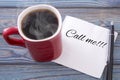 Inscription on a napkin Call me. and coffee in a red cup. Against a background of blue wood Royalty Free Stock Photo