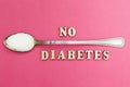 The inscription `no diabetes`, a spoon with sugar on a pink background, concept