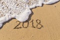 Nscription Number 2018 handwritten on seashore sand