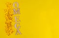The inscription omega made of wooden beech and fish oil capsules on a yellow background. Copy space.