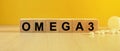 The inscription omega3 on wooden cubes, bright yellow background.