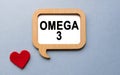 The inscription OMEGA 3 on a wooden template, against the background of scattered a red heart. Medical concept