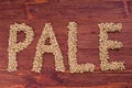 The inscription of pale by malt grains on wood background. Craft