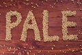 The inscription of pale by malt grains on wood background. Craft