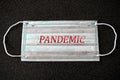 Inscription PANDEMIC on a medical mask. Novel coronavirus outbreak. Prevention of covid. Global pandemic alert. Covid-19 spread