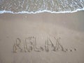 The inscription `Relax...` on a sandy beach