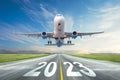 Inscription on the runway 2023 surface of the airport road yellow line take off airplane. Concept of travel in the new year,