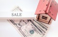 The inscription sale as a sign of a house sold for money, on a background of a wooden house with dollars Royalty Free Stock Photo