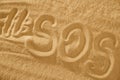 Inscription on the sand beach SOS with hashtag. Space for text Royalty Free Stock Photo