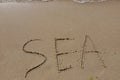 The inscription sea on the sand by the water and the rising wave, seashore beach vacation by the sea Royalty Free Stock Photo