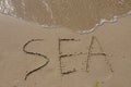 The inscription sea on the sand by the water and the rising wave, seashore beach vacation by the sea Royalty Free Stock Photo