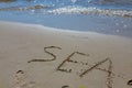 The inscription sea on the sand by the water and the rising wave, seashore beach vacation by the sea Royalty Free Stock Photo