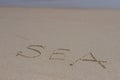 The inscription sea on the sand by the water and the rising wave, seashore beach vacation by the sea Royalty Free Stock Photo