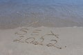 The inscription sea 2022 on the sand by the water and the rising wave, seashore beach vacation by the sea Royalty Free Stock Photo