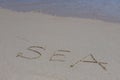 The inscription sea on the sand by the water and the rising wave, seashore beach vacation by the sea Royalty Free Stock Photo