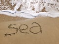 Inscription Sea on the sandy beach and foamy sea water Royalty Free Stock Photo