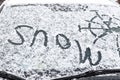 The inscription snow, on the front windshield of the car, covered with snow