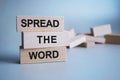 The inscription SPREAD THE WORD on wooden cubes isolated on a light background, the concept of business and finance