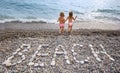 Inscription from stones BEACH at coast, two girls Royalty Free Stock Photo