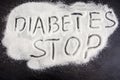 The inscription `stop diabetes` on white sugar. Sugar on a black background. Disease Warning.