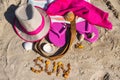 Inscription sun made of amber and different accessories for relax on sand. Straw hat, slippers and towel. Summer time on beach