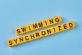 The inscription swimming synchronized written on yellow cubes against blue background.