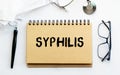 Inscription - SYPHILIS. Written in a notepad to remind you of what`s important. Top view of the table along with a stethoscope an